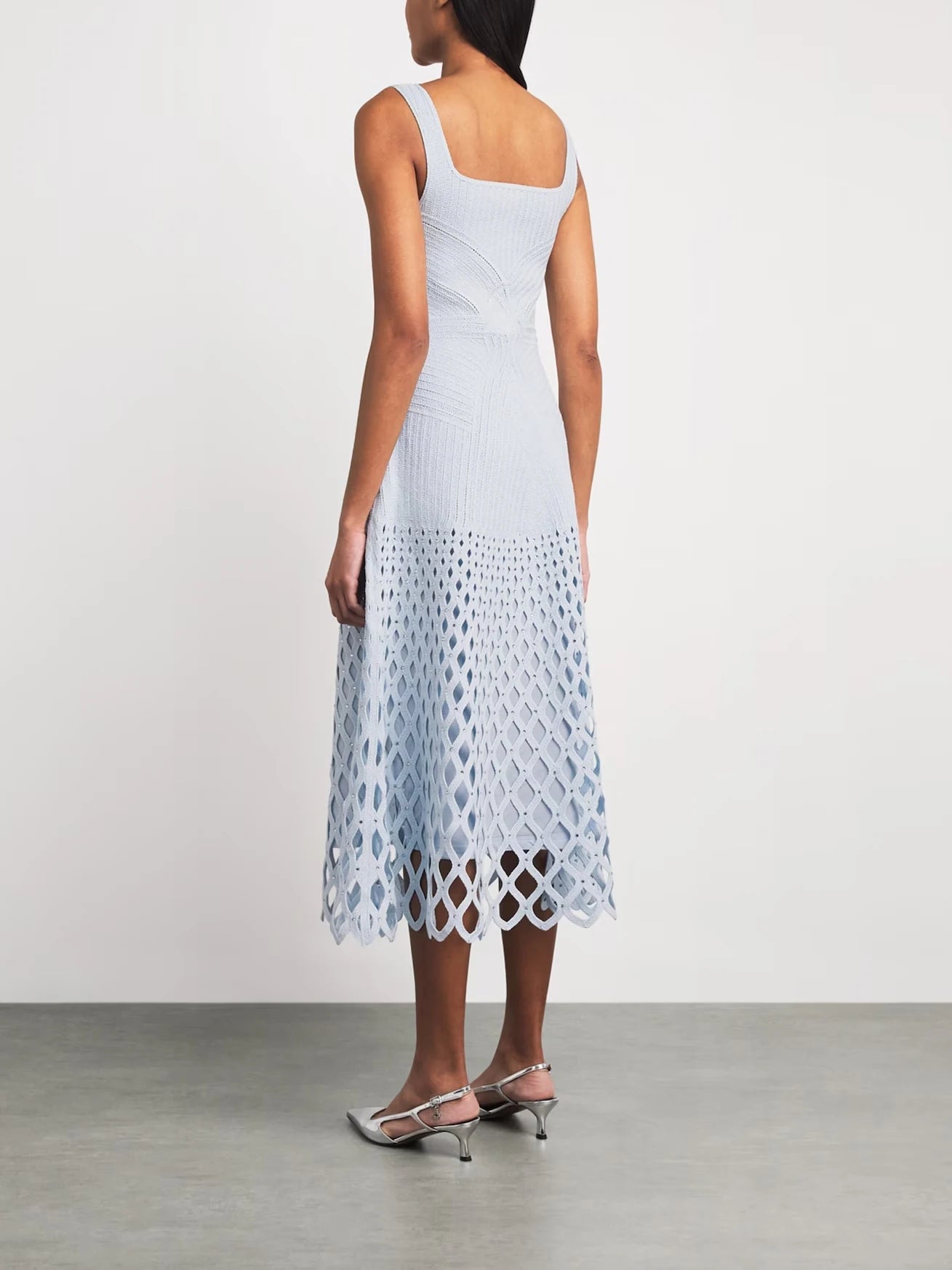 Woman wearing a light blue dress with a geometric pattern on a plain background