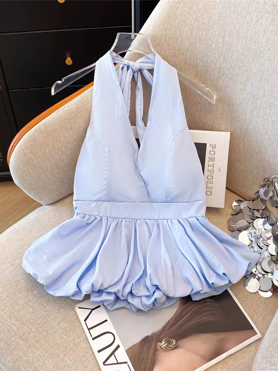 Light blue halter-style dress on a beige chair with a magazine underneath.